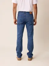 Pantalón de jean corte recto en color azul medio, con cierre de botón y cremallera, y bolsillos laterales y traseros.