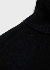 Vestido corto de punto grueso en color negro, con cuello alto y mangas largas. Presenta un diseño entallado con textura acanalada en las mangas.