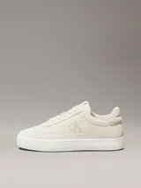 Zapatillas urbanas Calvin Klein modelo Classic Cupsole, color crema, con capellada de cuero gamuzado, interior de espuma, forro de malla de poliéster y suela de TPR. Presentan cordones, detalle de pala vega, lengüeta trasera acolchada y logo CK en el lateral.