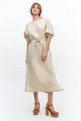 Vestido midi color coral confeccionado en lino. Tiene corte recto, mangas abullonadas con detalle de tablas en el puño, tajos laterales y lazo en la cintura.