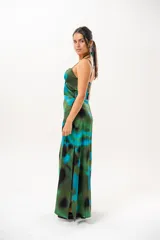 Vestido largo con estampado abstracto en tonos verdes, azules y negros. Presenta tirantes finos y cuello halter cruzado con detalle de abertura en el pecho.