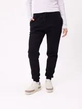 Babucha de estilo deportivo en color negro, con cintura elástica ajustable mediante cordón, bolsillos laterales y puños acanalados en los tobillos.