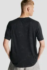 Remera deportiva negra de corte estándar y manga corta, con cuello redondo. Presenta un tejido funcional con tecnología DryMove™ y un sutil estampado jaspeado en tono más oscuro.