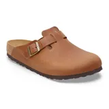 Zueco tipo mule de cuero color cognac, con tira ajustable sobre el empeine y hebilla metálica. Presenta plantilla de corcho y suela de goma antideslizante.