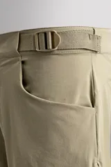 Pantalón corto de estilo técnico, color beige, con ajuste regular. Cuenta con cintura ajustable mediante cinturón de doble hebilla, cierre frontal con cremallera y botón a presión, bolsillos laterales y bolsillos con cremallera oculta.