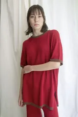 T-shirt de tejido artesanal color rojo intenso, con cuello redondo y bordes en color marrón. Presenta mangas cortas y un calce holgado.