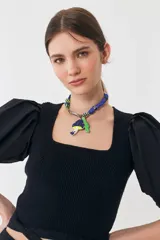 Top tejido negro con escote recto y mangas balloon de poplín. Tiene tiras tejidas para ajustar en la cintura.