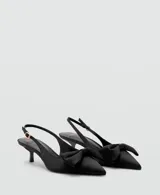 Zapato de tacón tipo slingback en color negro, con diseño destalonado, puntera fina y un detalle de lazo en la parte delantera. Cuenta con tira ajustable en el talón con hebilla metálica dorada y taco fino de altura baja.