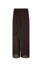 Pantalón de punto color chocolate, de corte recto y tiro alto. Presenta una superposición frontal cruzada con lazo lateral en la cintura, textura tejida con ligera transparencia en el dobladillo y detalle de ribete de encaje en la parte inferior.