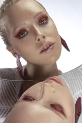 Par de aros colgantes con forma de hoja alargada, color marrón rojizo con textura acanalada.