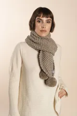 Bufanda tejida a mano en punto arroz color crudo, con detalle de pompón en uno de los extremos.