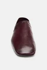 Zapato plano tipo slipper confeccionado en piel color bordó, con diseño de copete subido, punta cuadrada y talón flexible que permite su uso como destalonado.