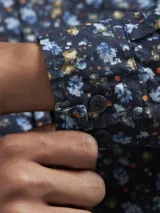 Camisa de hombre azul marino con estampado floral en tonos celeste y amarillo, de manga larga y corte clásico.