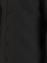 Camisa negra de algodón elástico mercerizado, corte slim, cuello en punta, puños segados, bajo redondeado y botones de nácar.