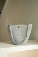Bolso de mano tipo tote, confeccionado en soga de algodón con diseño a rayas horizontales en degradé de color marrón y beige. Asas de hombro amarillas y cierre con broche de bronce.