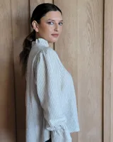 Blusa de algodón con cuello mao y volados, mangas largas con puños elásticos y corte holgado.