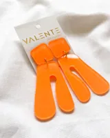 Aros colgantes de acrílico color naranja, con forma geométrica irregular.