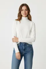 Polera blanca de algodón y elastano, corte ajustado y cuello alto.