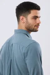 Camisa de lino de manga larga en color beige, con cuello camisero, cierre frontal de botones y un bolsillo ojal en el pecho.