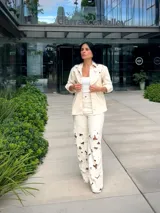 Camisa color off-white con detalles calados en forma de flores en los hombros y cuello. Tiene cierre frontal con botones a presión y cordón decorativo.