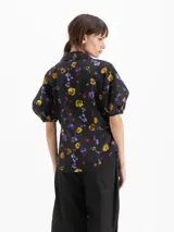 Camisa de poplín negro con estampado floral multicolor, de calce entallado, cuello clásico y mangas cortas abullonadas con puños elásticos.
