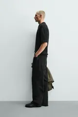 Polo de punto color negro con textura irregular, cuello solapa con abertura frontal, manga corta y acabados en rib, de corte relaxed fit.