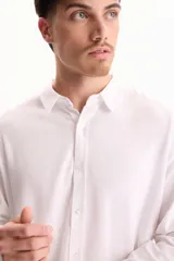 Camisa de lino de manga larga, color beige, con cuello clásico y cierre frontal de botones.