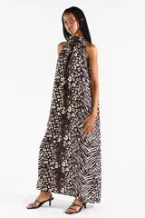 Vestido largo con cuello halter y estampado animal print combinando patrones de leopardo y cebra en tonos negro y crudo. Presenta diseño sin mangas y caída fluida.