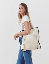 Bolso tipo tote bag de lienzo color crudo, con vivos en cuerina negra y estampado vertical con el texto "LA OPERA".