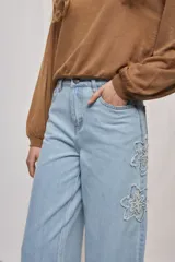 Jean wide leg blanco de tiro medio, con calce amplio y detalle de flores bordadas en los laterales.