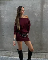 Minivestido color borgoña, con escote off-shoulder y mangas largas. Se ajusta a la cintura con un cinturón negro con tachas plateadas.