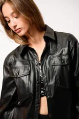 Chaqueta tipo camisa de cuero sintético color negro, con bolsillos frontales y broches metálicos.