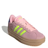 Championes Adidas modelo VL Court Bold de plataforma, con capellada de gamuza en tono rosado. Presenta las icónicas tres tiras laterales en color verde neón con bordes oscuros, cordones al tono y suela de plataforma de goma en color marrón claro.