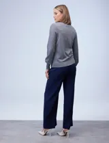 Buzo tejido en hilado fino, color gris, con cuello redondo y mangas largas plisadas.