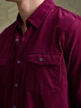 Camisa de pana color azul marino, con mangas largas, cuello clásico y dos bolsillos frontales con solapa y botón.