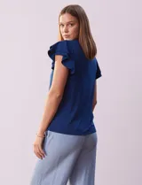 Blusa blanca de modal Rio & Rian con cuello a la base, escote en V con aplique metálico y mangas cortas con volados en capas.