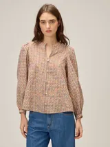 Camisa de manga larga con diseño a cuadros multicolor, cuello redondo con pequeña abertura frontal y cierre de botones. Presenta mangas con sutiles frunces en los hombros y puños ajustados.