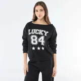 Buzo de felpa color negro con cuello redondo amplio y mangas largas. Presenta un estampado frontal en color blanco con la palabra 'LUCKY', el número '84' y tres estrellas.
