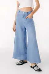 Pantalón de lino azul claro, de tiro alto, con corte ancho y acampanado (tipo palazzo o campana) y cierre frontal con botón.