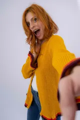 Saco de lana merino color mostaza, tejido a punto con detalle de volados en ruedo y puños. Tiene dos cierres frontales hechos en crochet a mano.