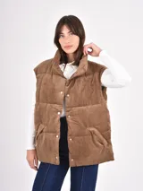 Chaleco puffer de pana color marrón, con cuello alto, bolsillos frontales y cierre de botones a presión.
