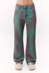 Pantalón de jean de tiro medio con estampado abstracto en tonos verdes y violetas.