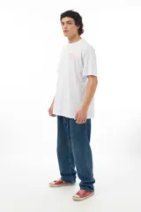 Remera blanca de algodón con estampa en la espalda de la Pantera Rosa cuidando bonsáis, con fondo de enrejado.