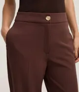 Pantalón zanahoria de poliéster y elastano color negro, de tiro alto, con cierre tradicional, bolsillos traseros y botón metálico con efecto martillado.