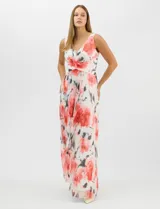 Vestido largo de chifón plisado con estampado floral en tonos rojos y grises sobre fondo blanco. Presenta escote en V pronunciado con panel de microtul, cintura drapeada con nudo central y falda amplia con capa frontal asimétrica. Incluye forro interior y cierre invisible en la espalda.
