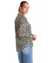 Camisa de manga larga con cuello solapa y cierre frontal de botones. Presenta un diseño estampado con patrón de cebra en tonos blanco y negro, puños abotonados y ruedo redondeado.