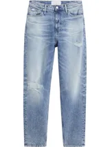 Jean de mezclilla azul claro con efecto lavado y zonas desgastadas/rotas en ambas piernas. Presenta un corte mom de talle alto, estilo clásico de cinco bolsillos y cierre de botón y cremallera.