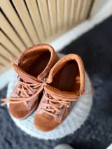 Botas Saura de cuero y gamuza en color tostado, con cordones frontales, suela gruesa y diseño tipo borceguí.