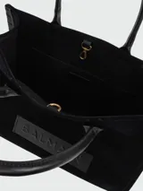 Cartera tote Balmain modelo B-Army Shopper Small, confeccionada en gamuza negra con detalles en cuero negro liso. Cuenta con doble asa superior, ribetes pespunteados y un parche frontal de cuero con el logotipo grabado en relieve.