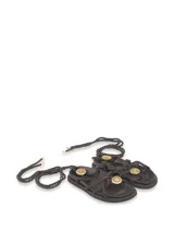 Sandalias chatas negras con tiras de soga y apliques dorados.